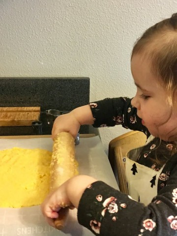 montessori child rolling out cheese dough with rolling pin