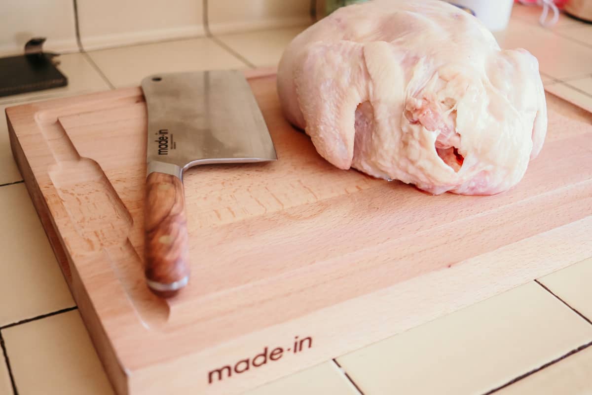 a whole chicken on a Made In butcher block with a butcher knife
