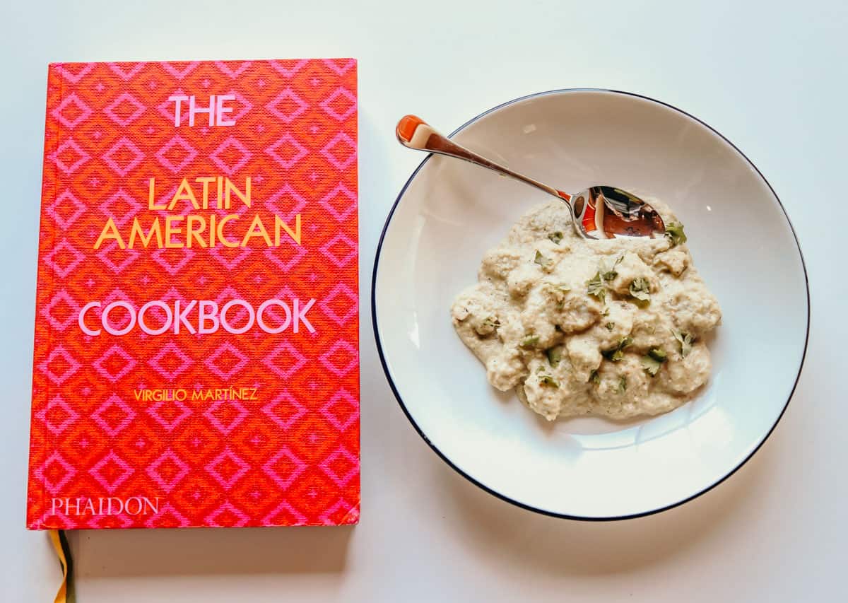 The Latin American Cookbook next to a bowl of Bahian chicken stew.