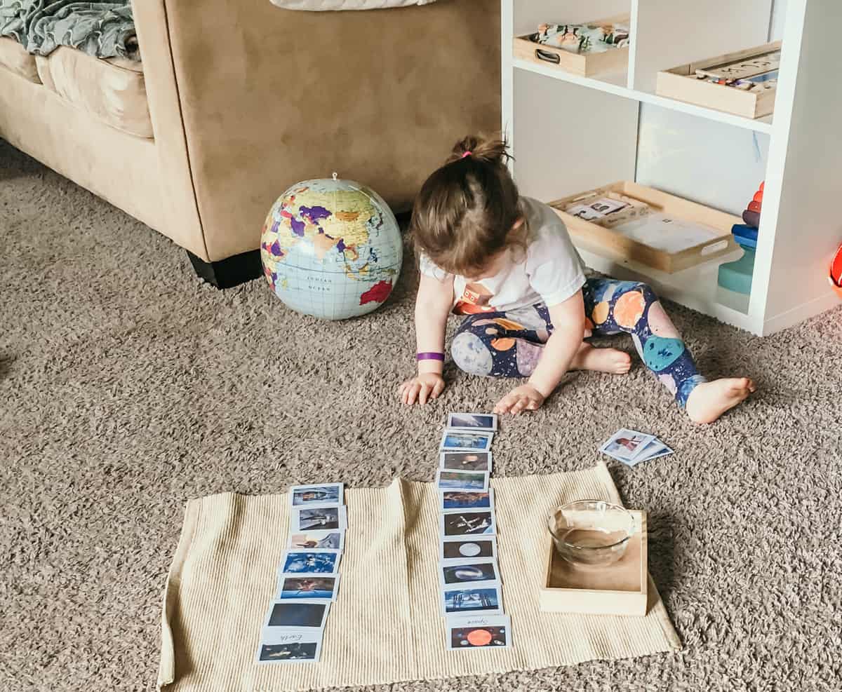 Montessori Child Sorting Earth vs Space cards on work mat