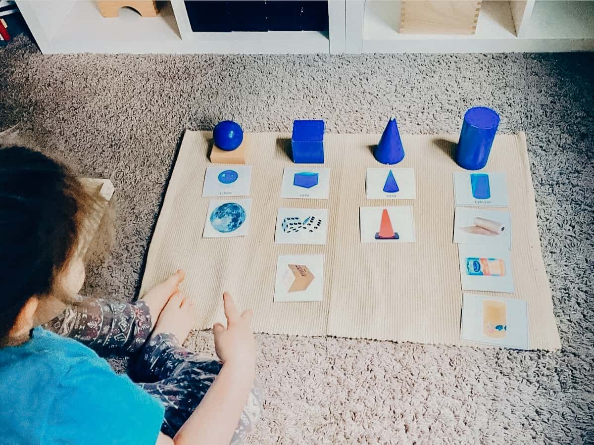 Child doing Sensorial Sorting Extension with Montessori geometric solids on a work mat