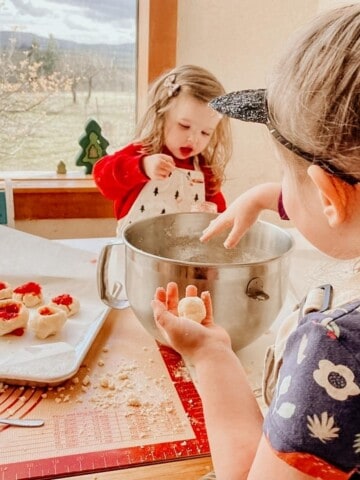 kids participating in an easy baking activity of rolling thumbprint cookies using a visual recipe