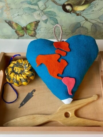 heart pillow with the continents on a Montessori tray with sewing tools
