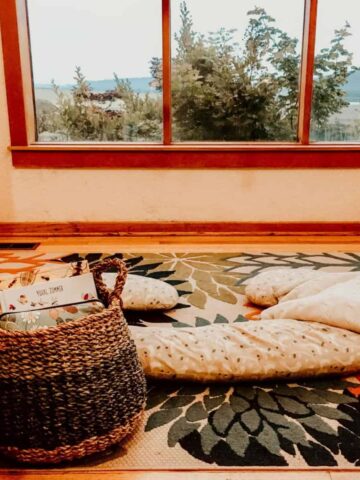 Summer Morning Basket with books and activities on a rug next to a pillow and blanket