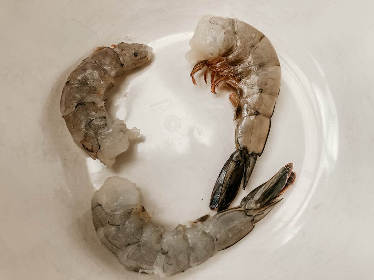 uncooked prawns in a bowl at various stages of being peeled