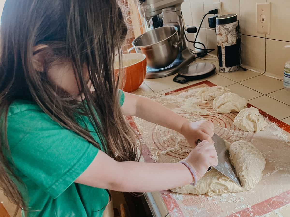 a child using a pastry cutter to separate dough into sections