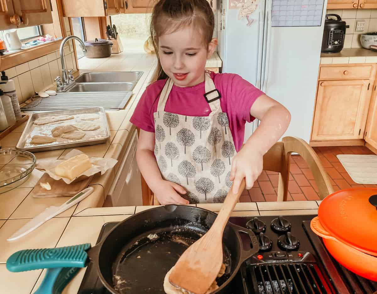 a child flattening bannock bread with a spatula