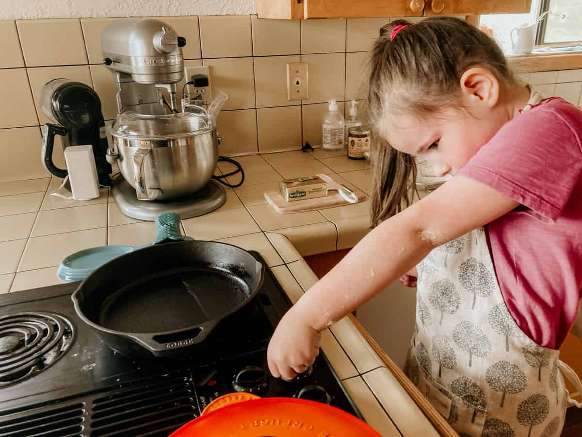 a child turning on a burner at the stove