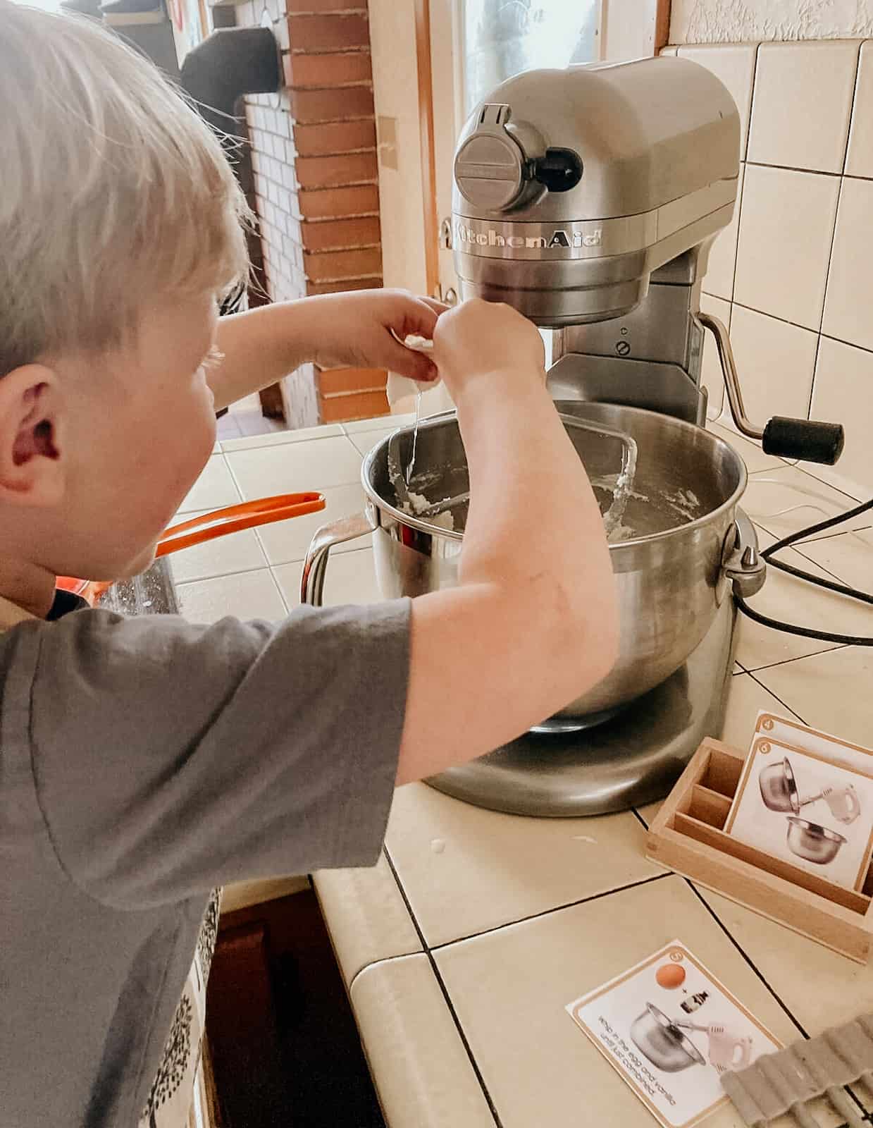 child cracking an egg into an electric mixer and following a visual recipe
