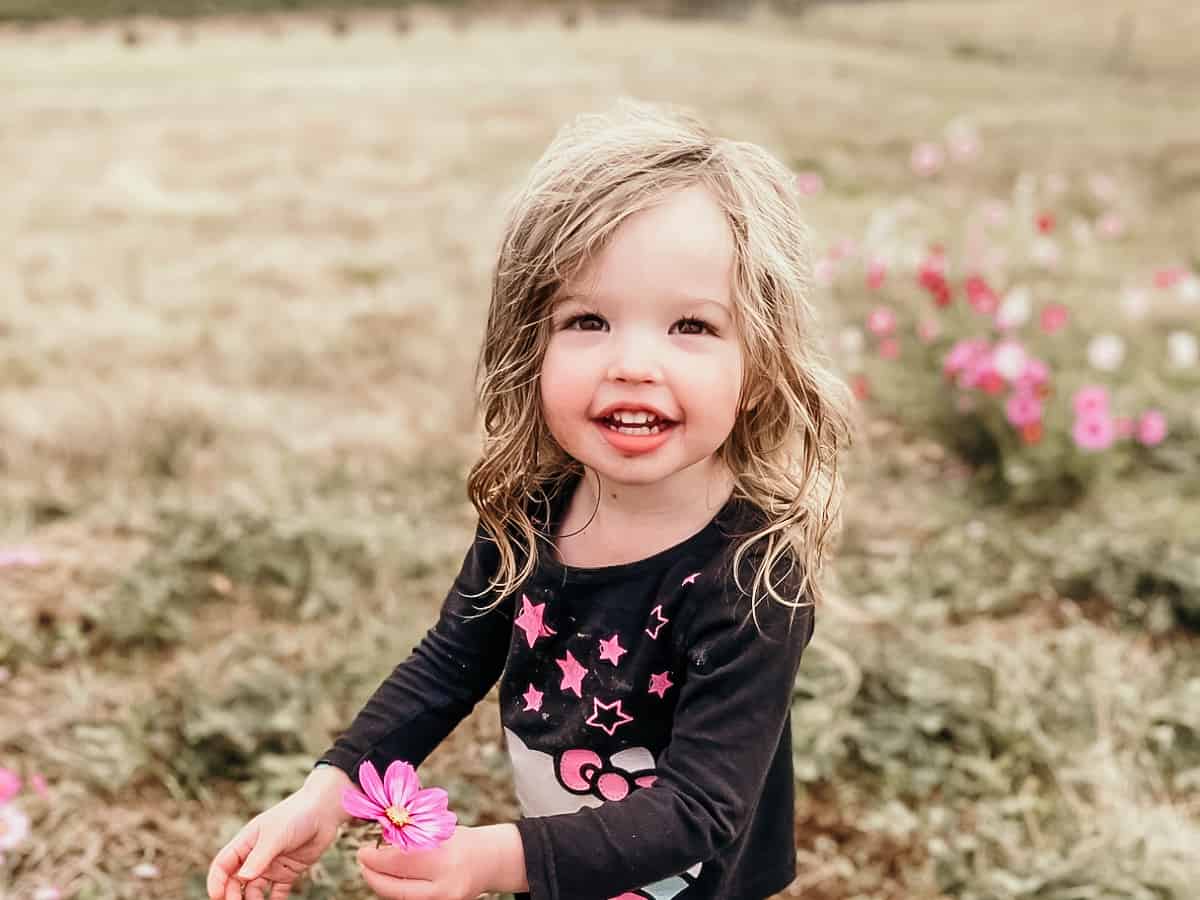 child standing in a field holding a flower