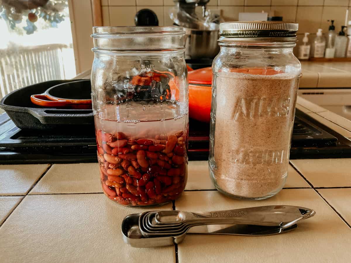 kidney beans in a mason jar with water on a counter beside a mason salt and measuring spoons