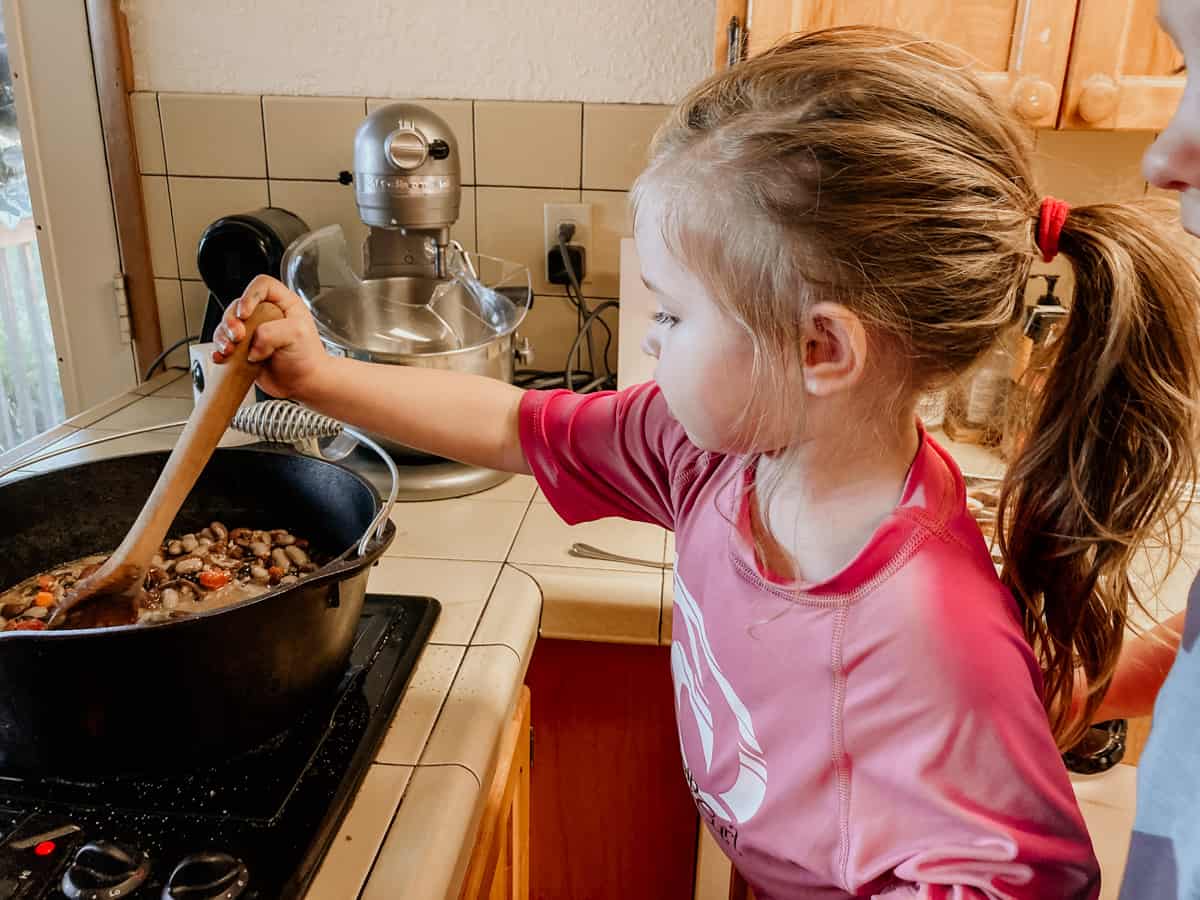 child stirring Three Sisters Bean Stew
