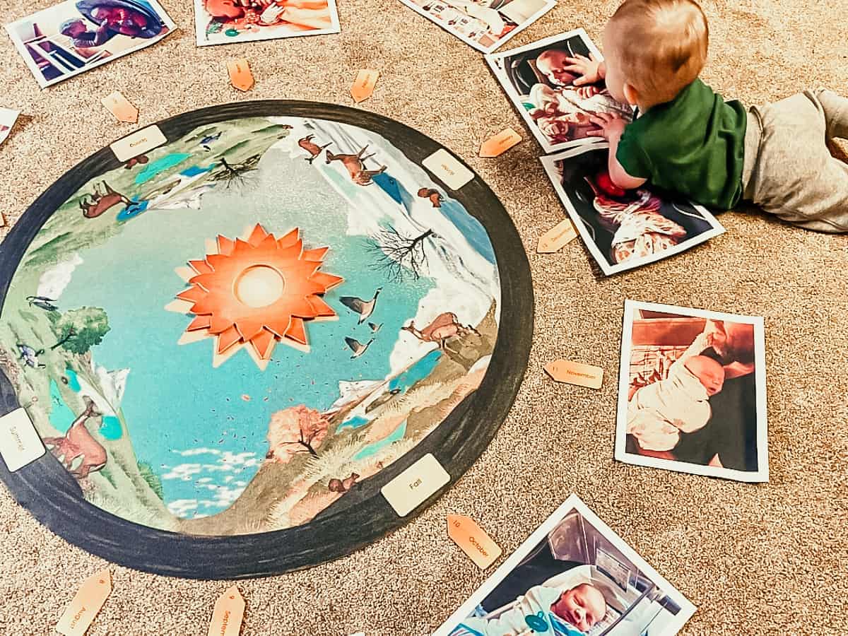 Child lying on the floor and touching picture next to a mat of seasons