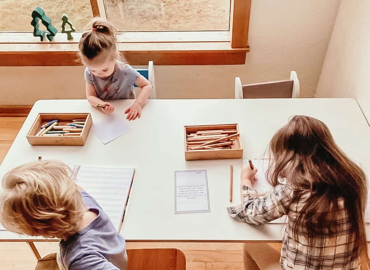 three children sitting at a table with paper, crayons, and pencils as an extension of the human history timeline