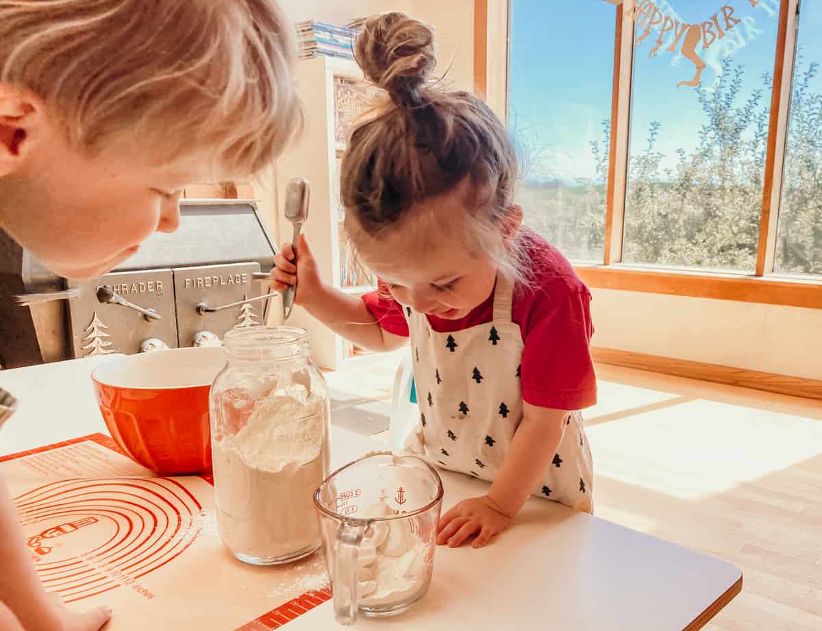 child adding einkorn flour to a measuring cup