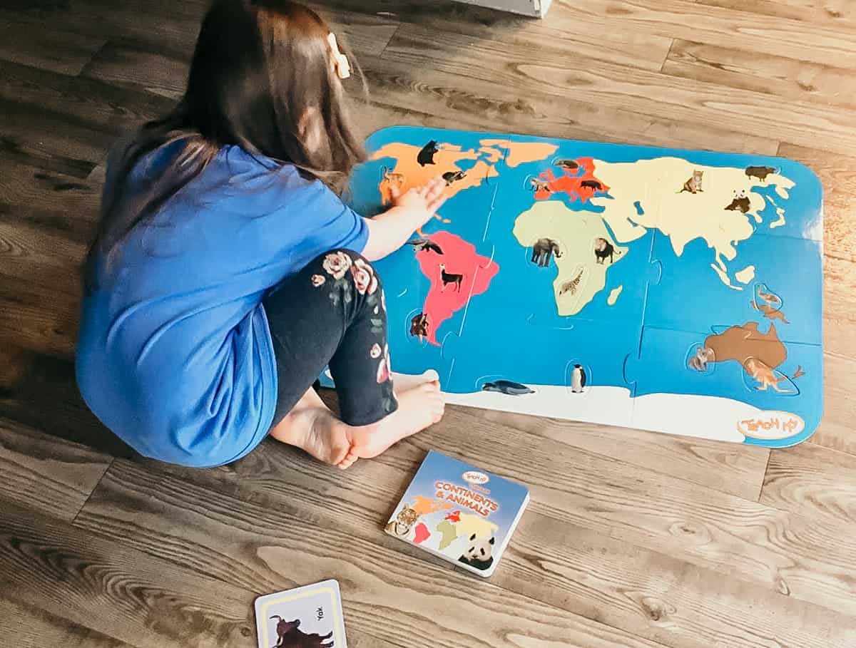 child working with a continents and animals puzzle
