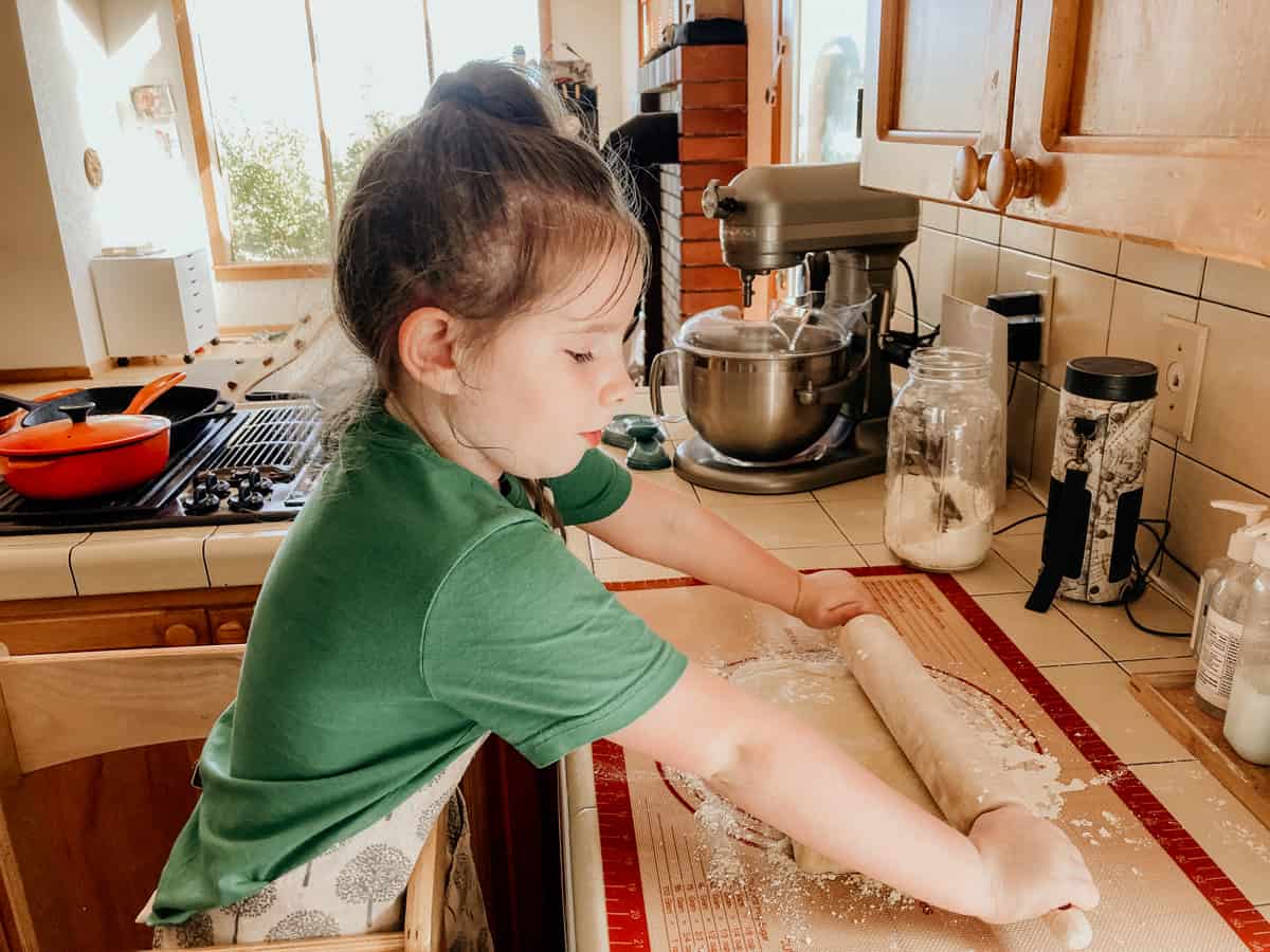 child rolling einkorn dough with a rolling pin