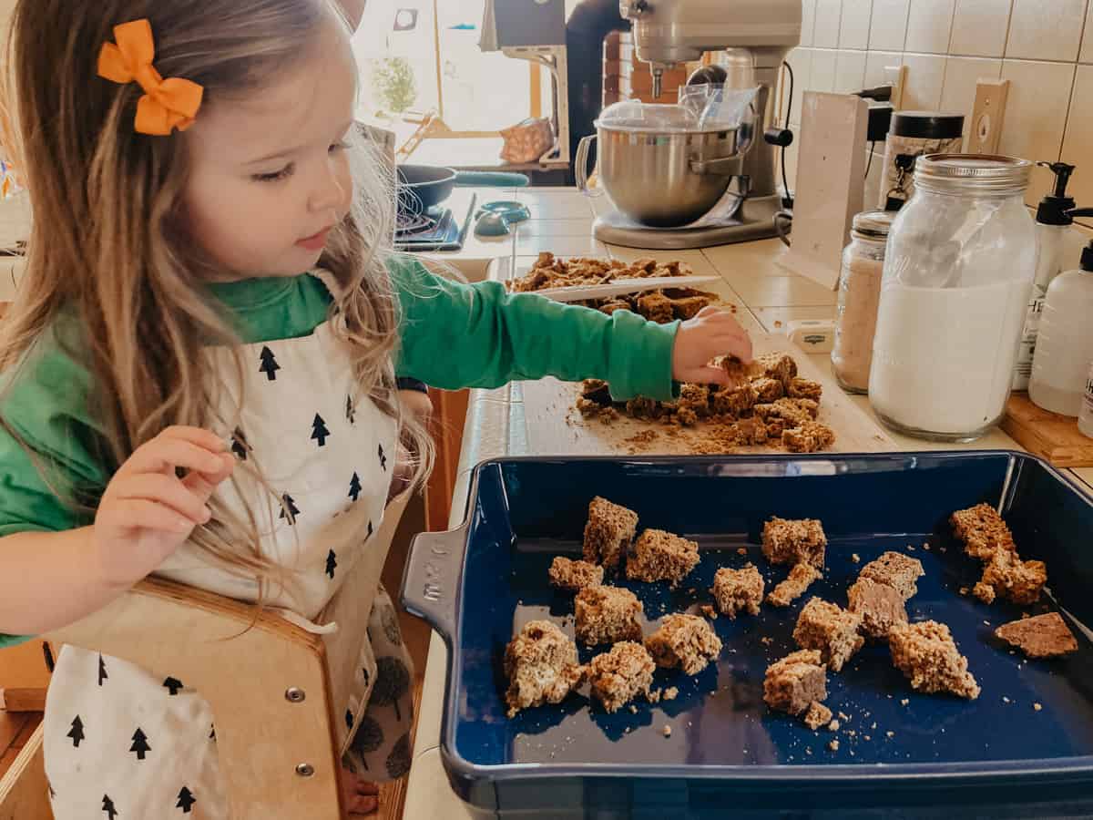 child adding pieces of pumpkin bread to a Made In rectangular baking dish