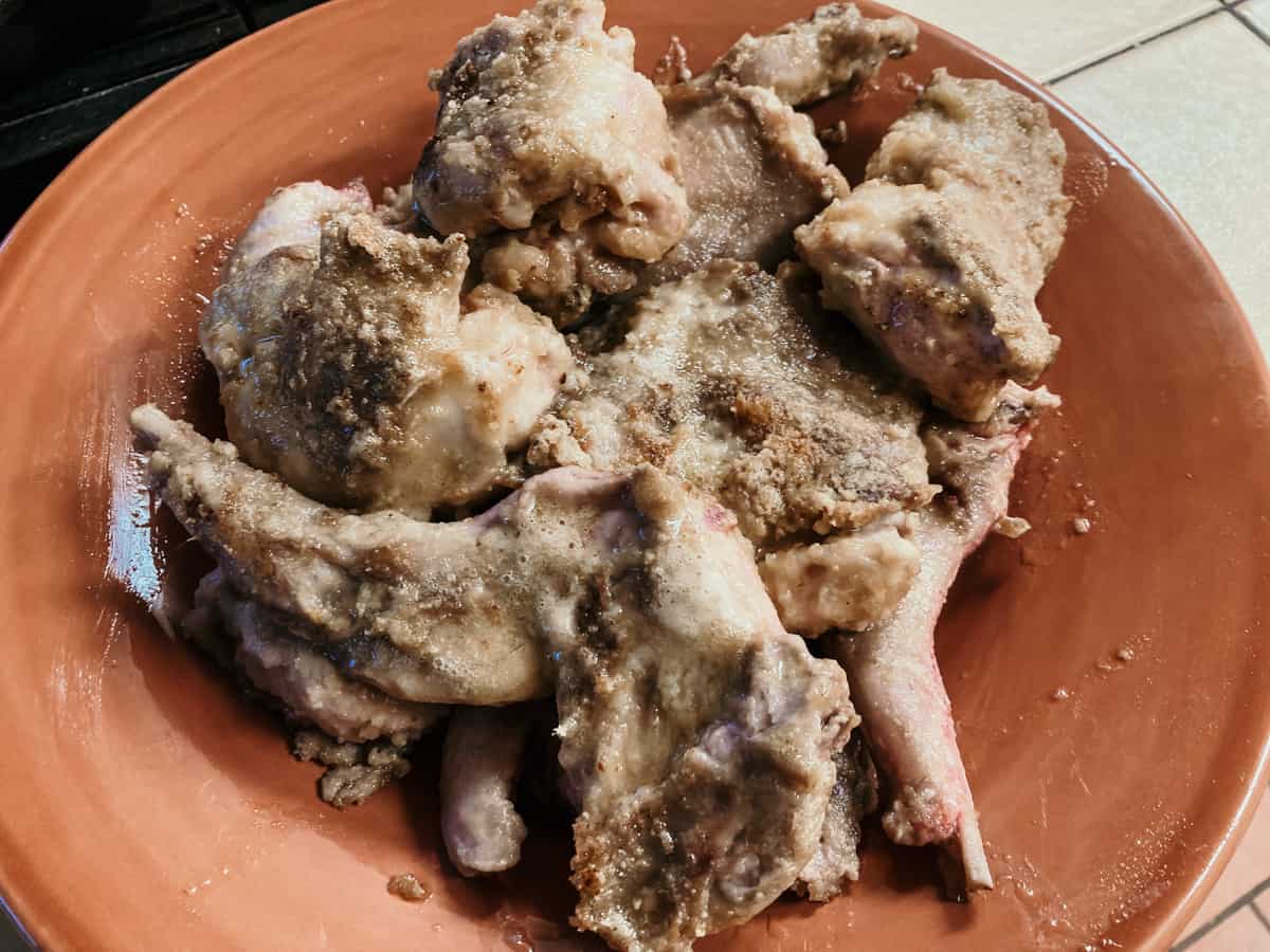 cuts of rabbit meat on a plate after browning in a dutch oven