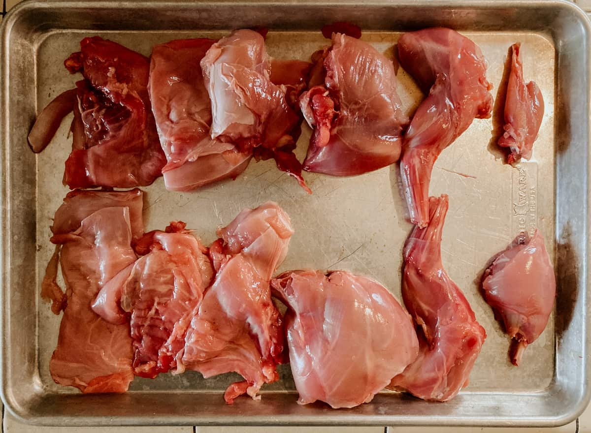 rabbit cut into 12 pieces and on a sheet pan