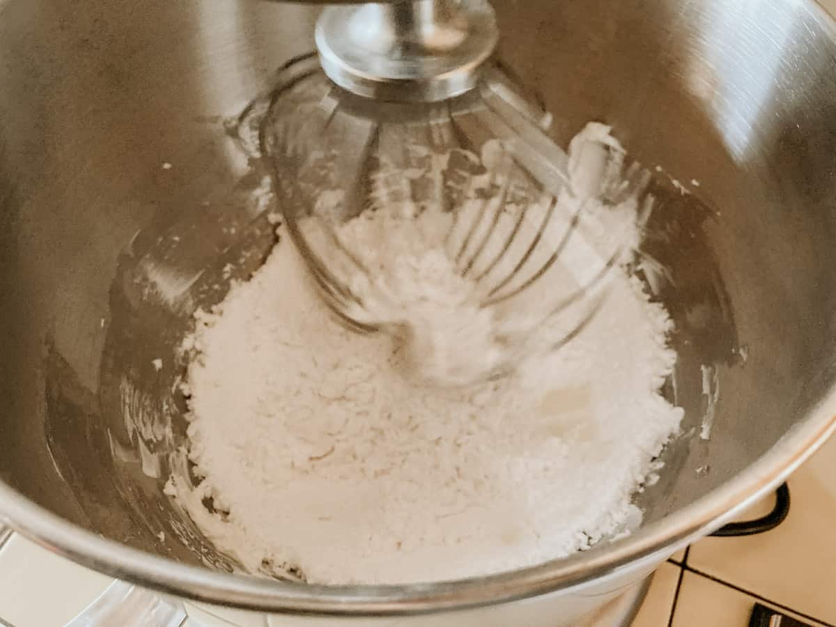 ingredients for making pound cake icing in a mixing bowl with a whisk attachment