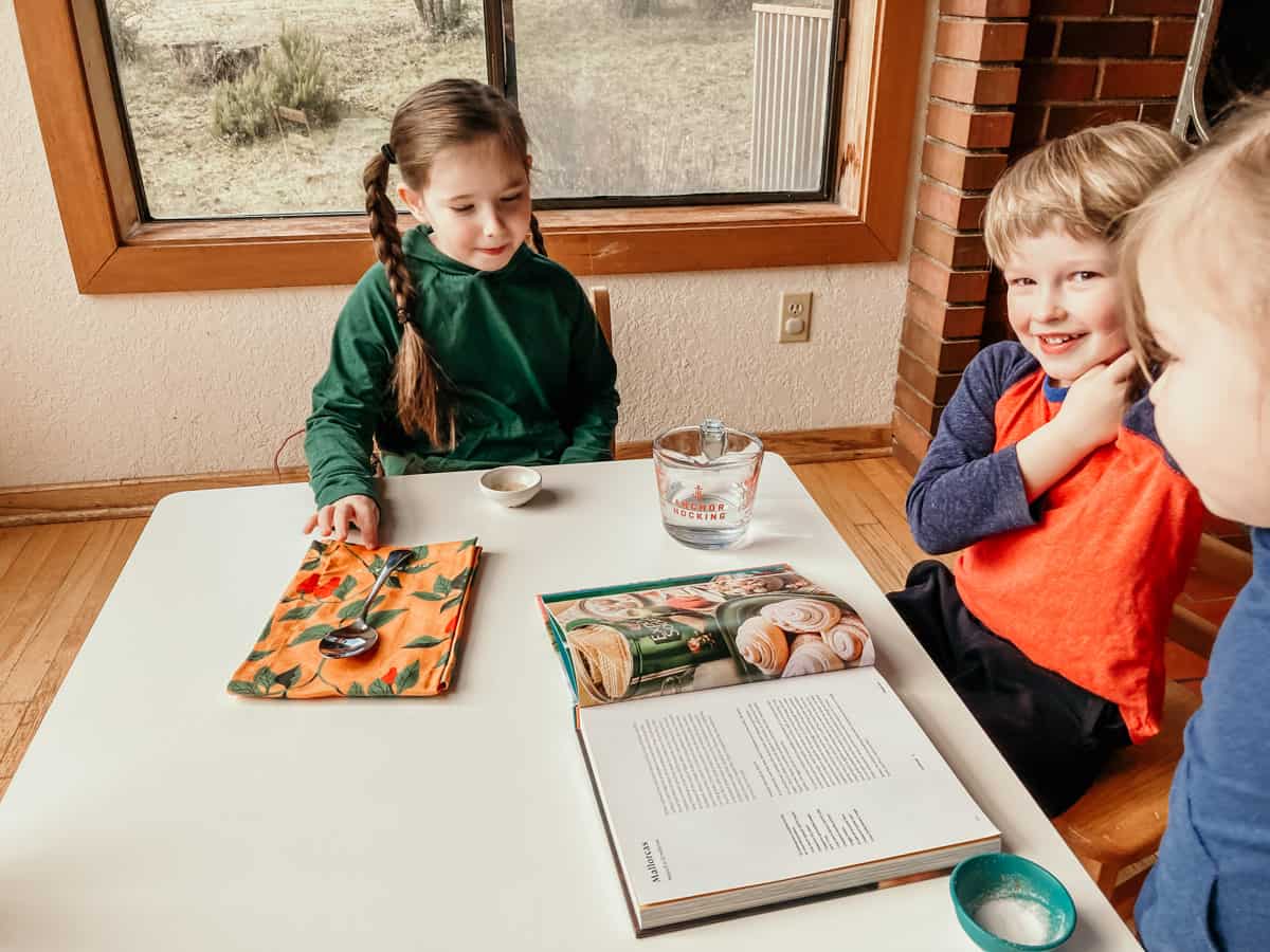 kids sitting at a table with ingredients and Diasporican Puerto Rican cookbook