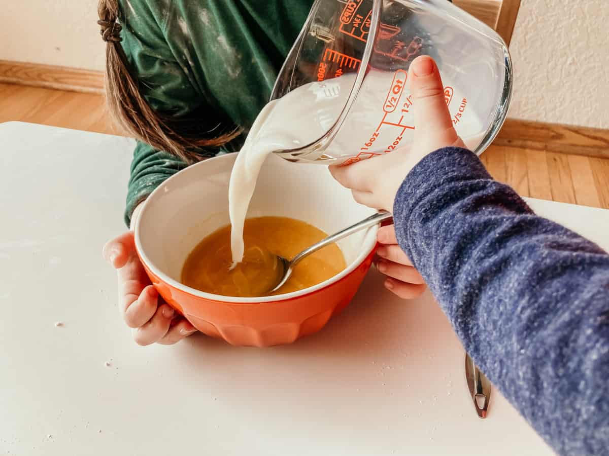 closeup of child pouring milk into a bowl