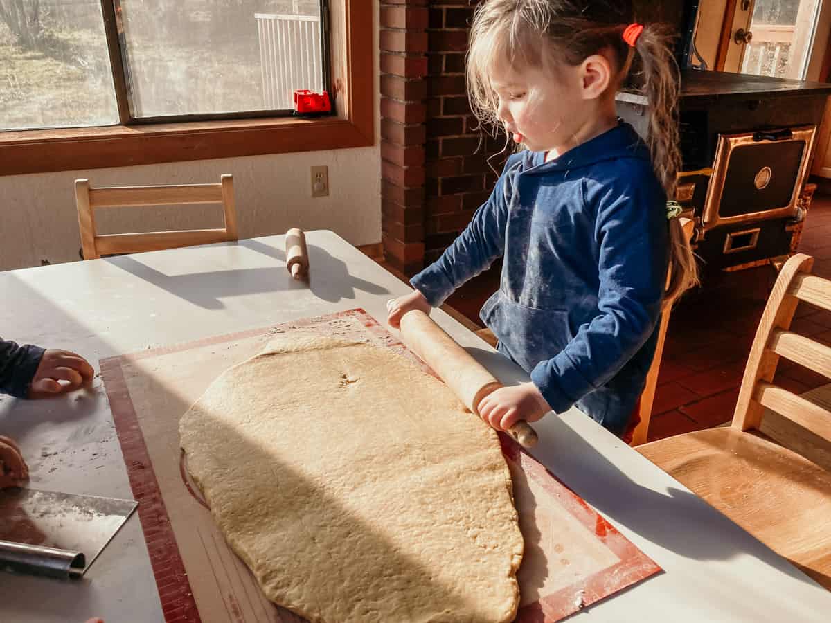 child rolling out dough with a rolling pin