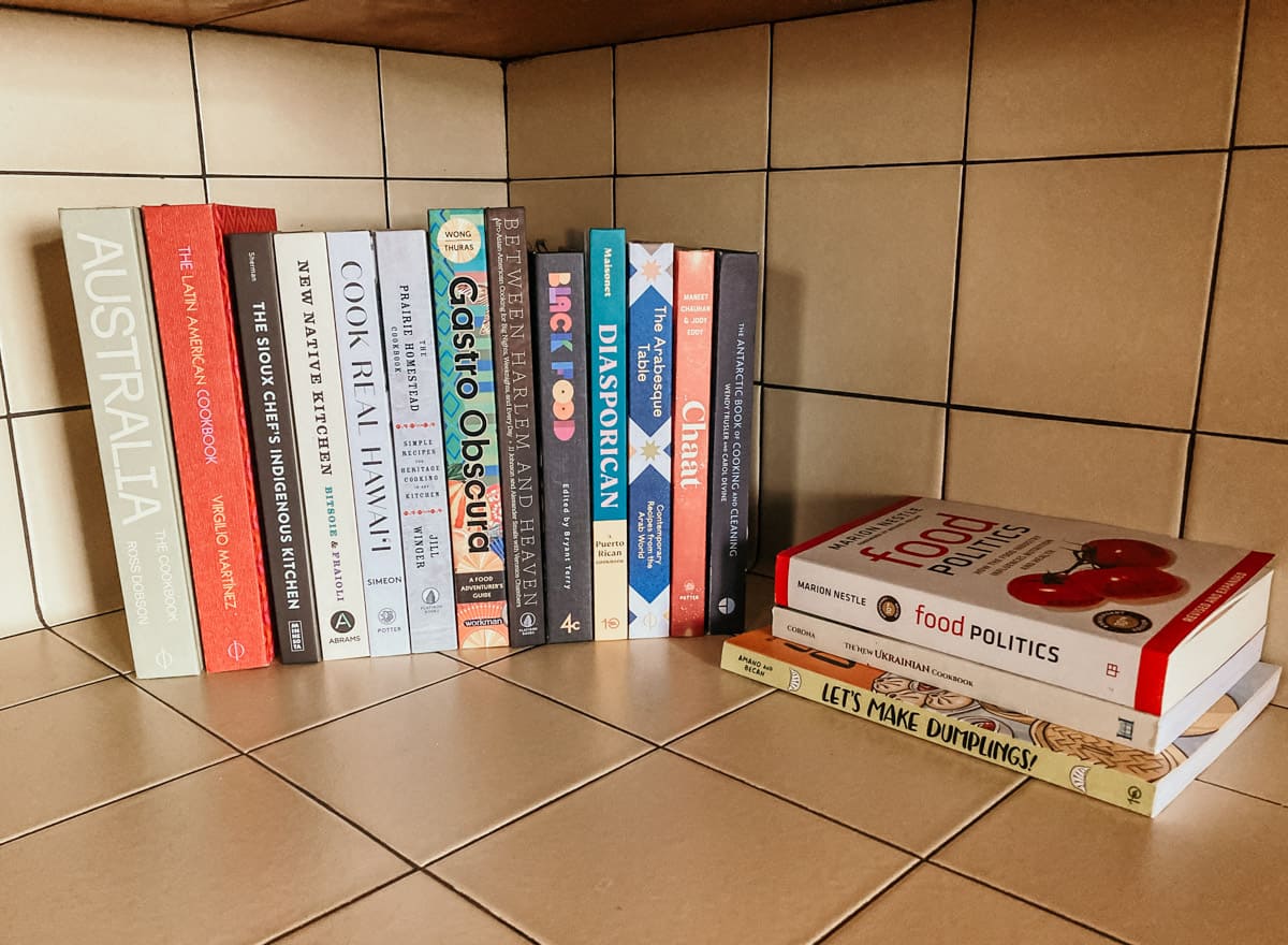 a collection of diverse cookbooks and food resources on a farmhouse kitchen counter