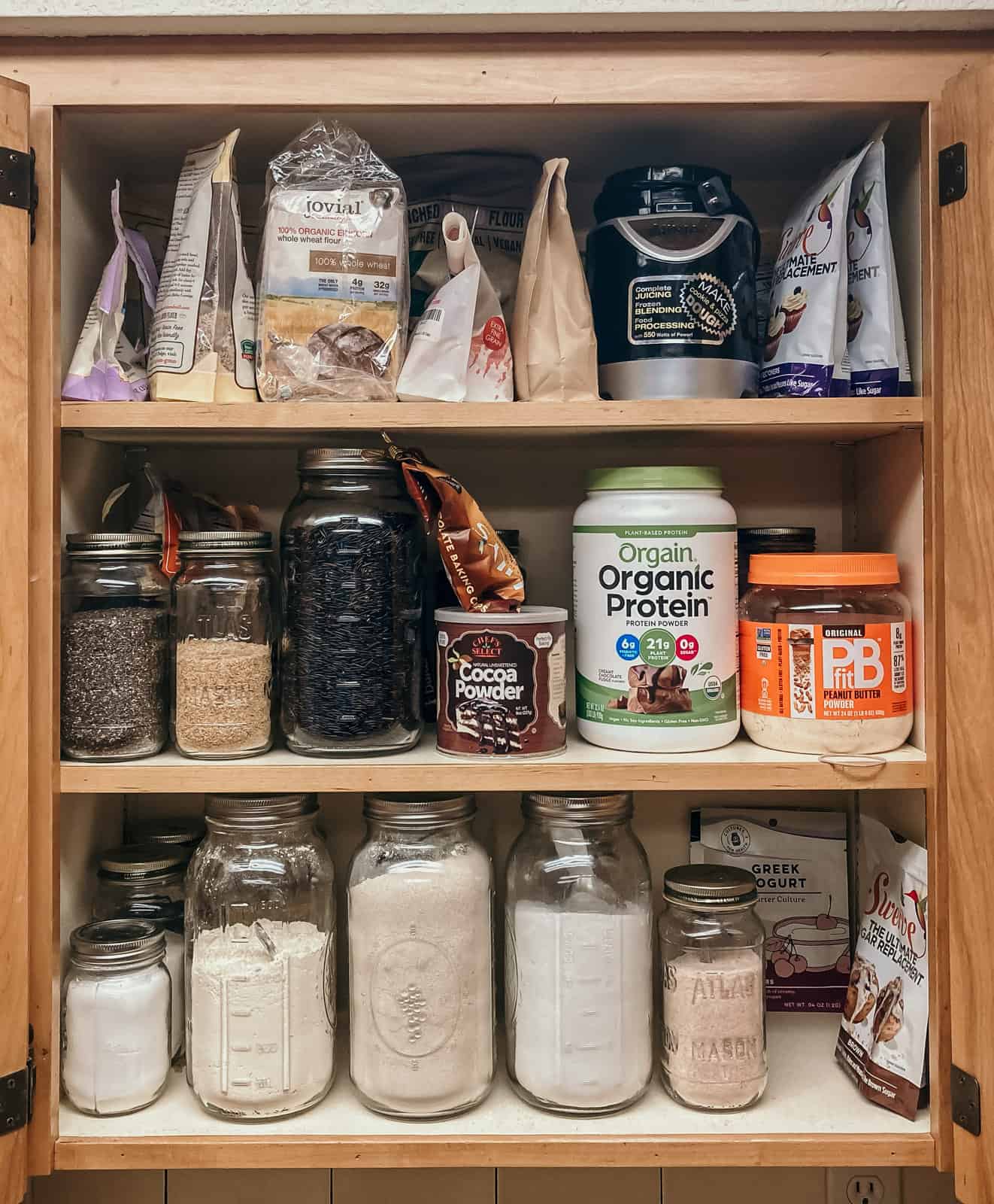 farmhouse kitchen cabinet containing flour, salt, sweeteners, and other ingredients