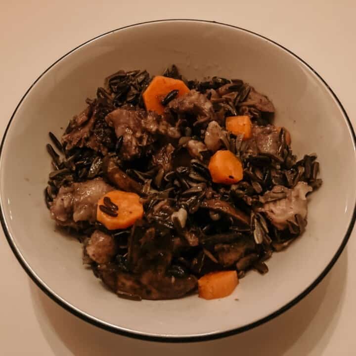 a bowl of braised oxtails, black rice, and vegetables