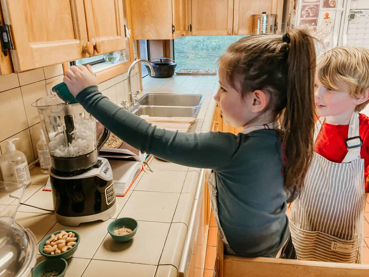 a child is adding ingredients to a blender