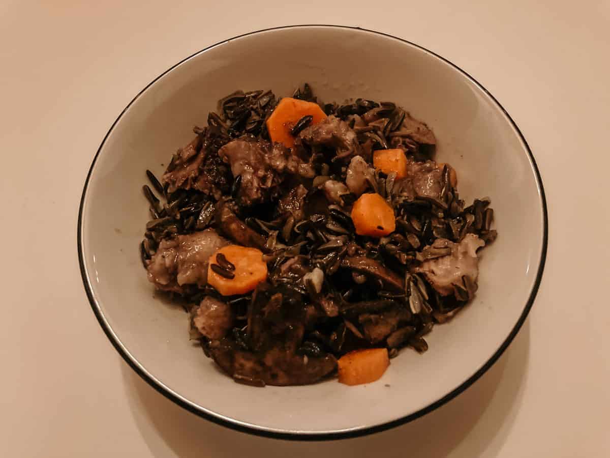 a bowl of braised oxtails, black rice, and vegetables