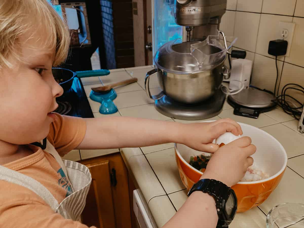 child cracking an egg over a bowl