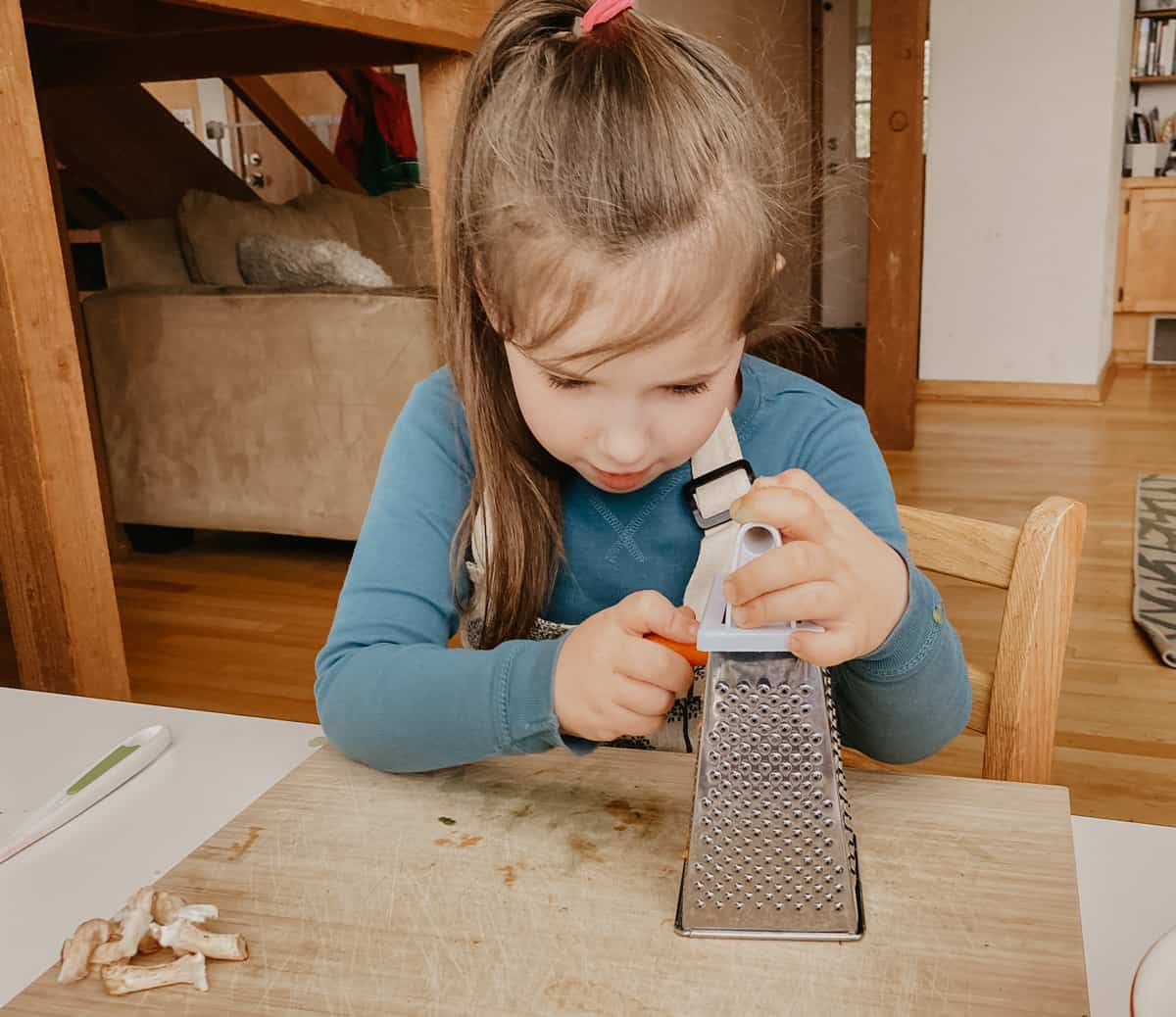 a child grating carrot using a box grater