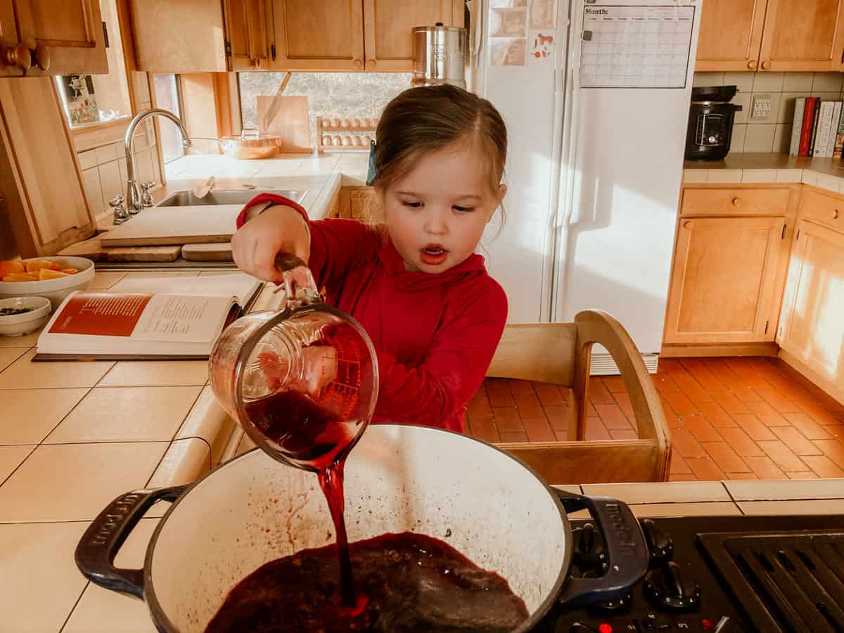 child pouring wine into a dutch oven