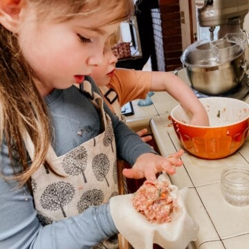 child wetting a dumpling wrapper containing a pork and shrimp mixture