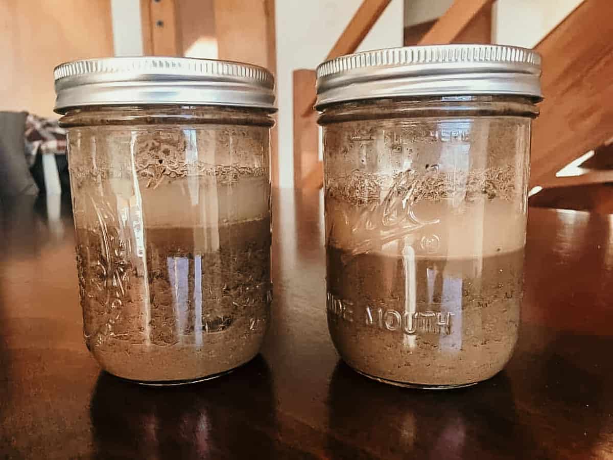 mason jars containing soil and water on a table