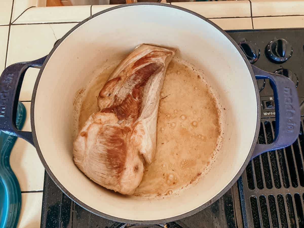 pork belly searing in a dutch oven