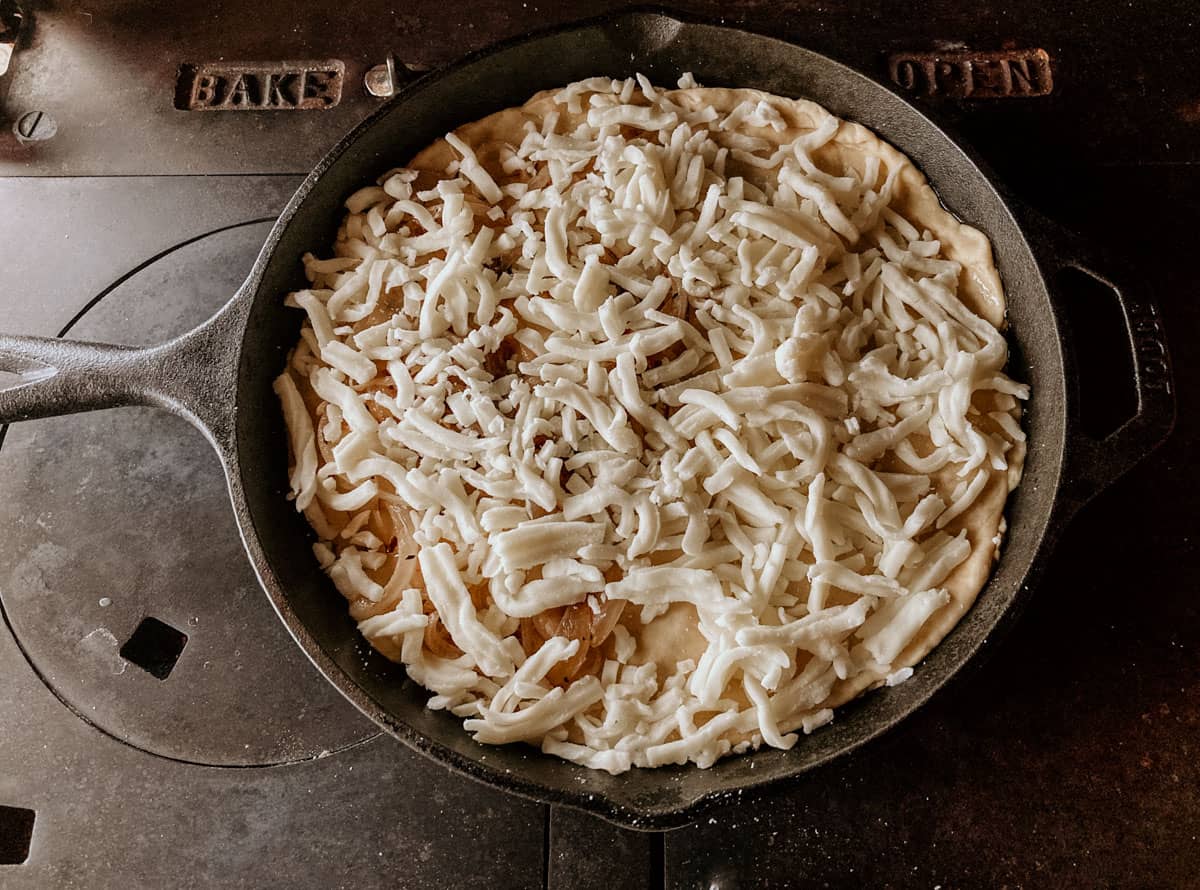 view of an uncooked stuffed crust cheese pizza in a cast iron skillet