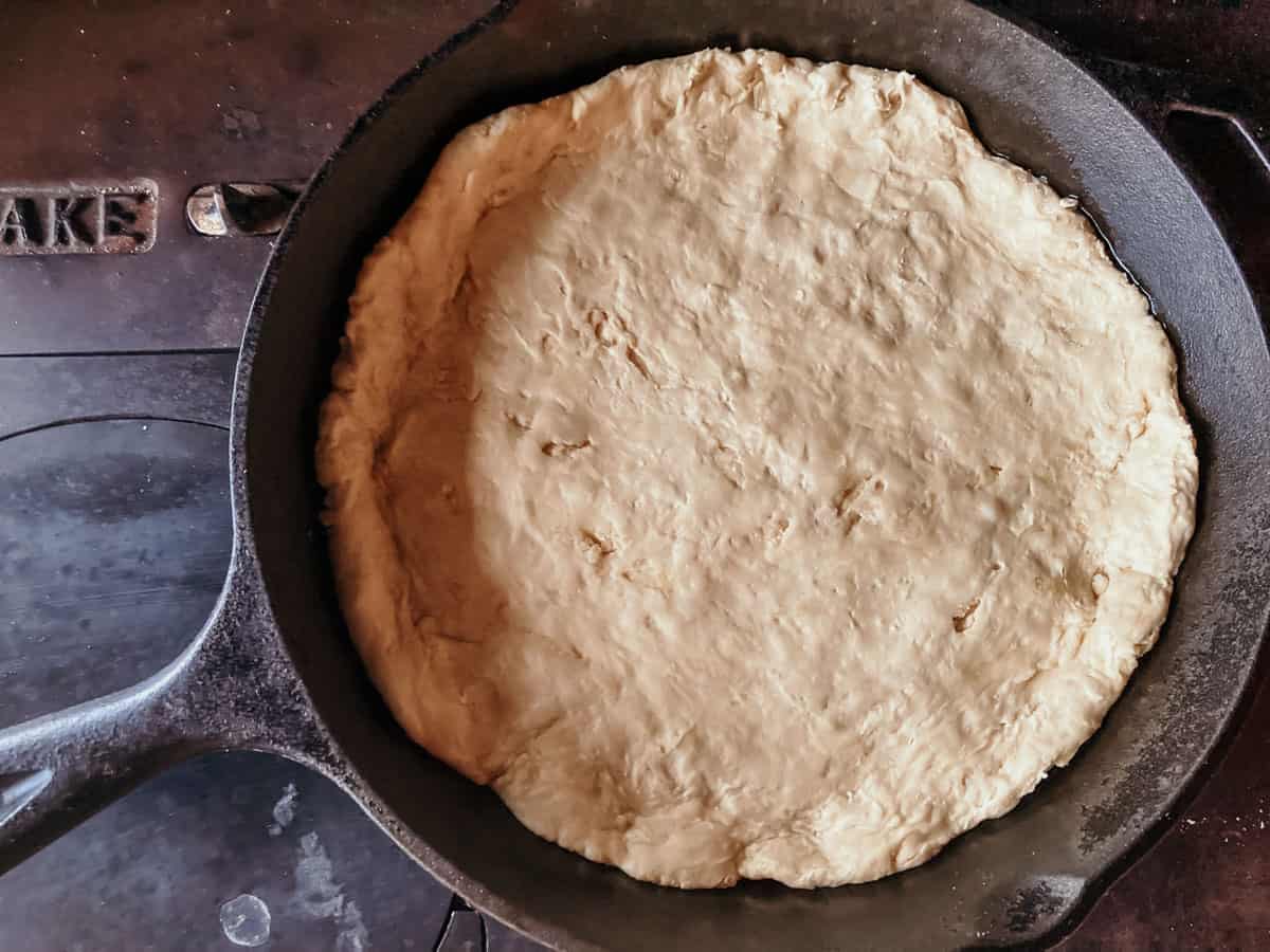 bottom layer of stuffed crust pizza dough in a cast iron skillet