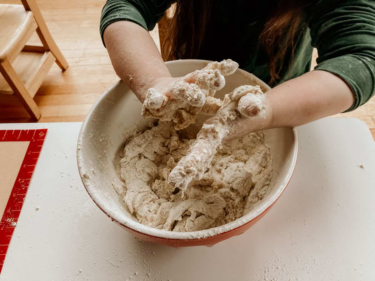 child's hands over a bowl of dough