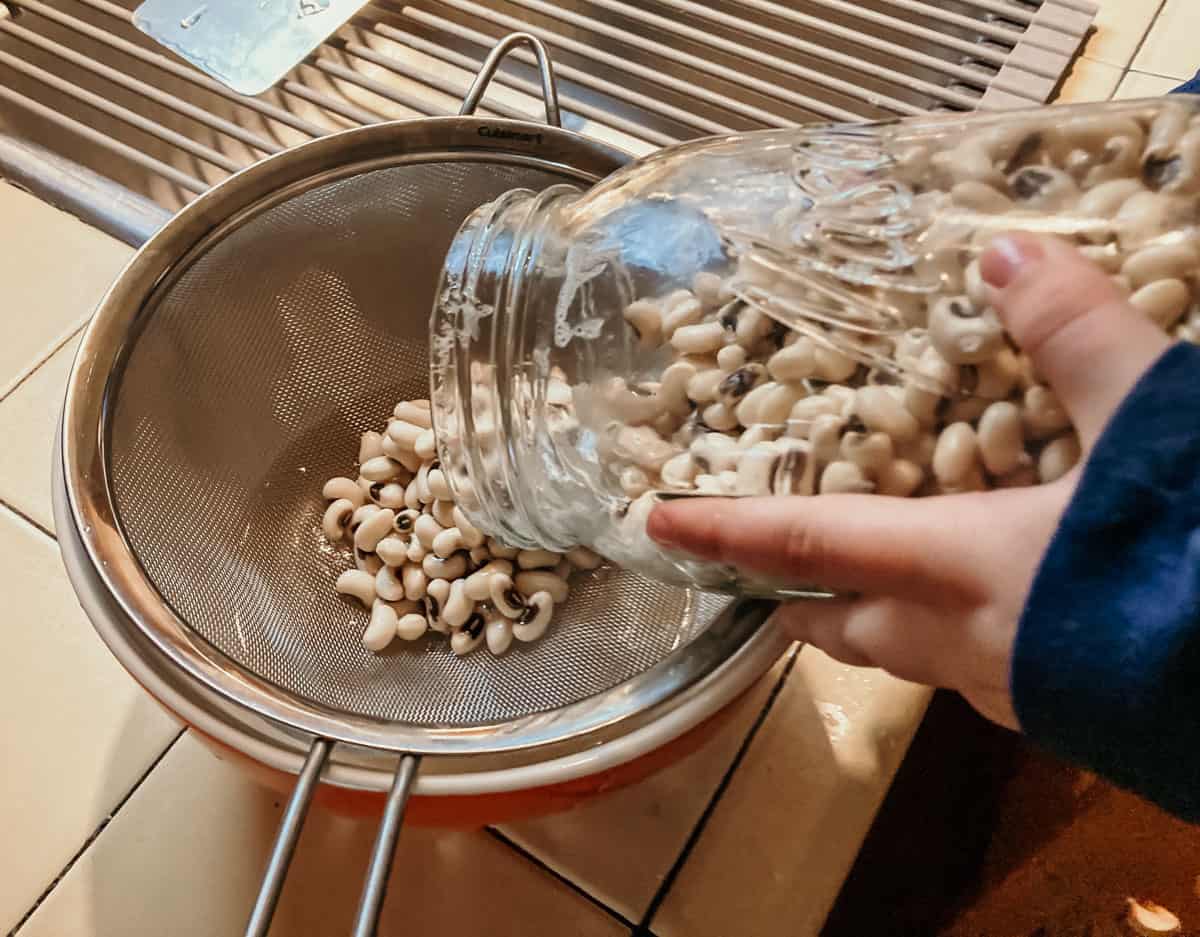 closeup of a child pouring black-eyed peas into a strainer