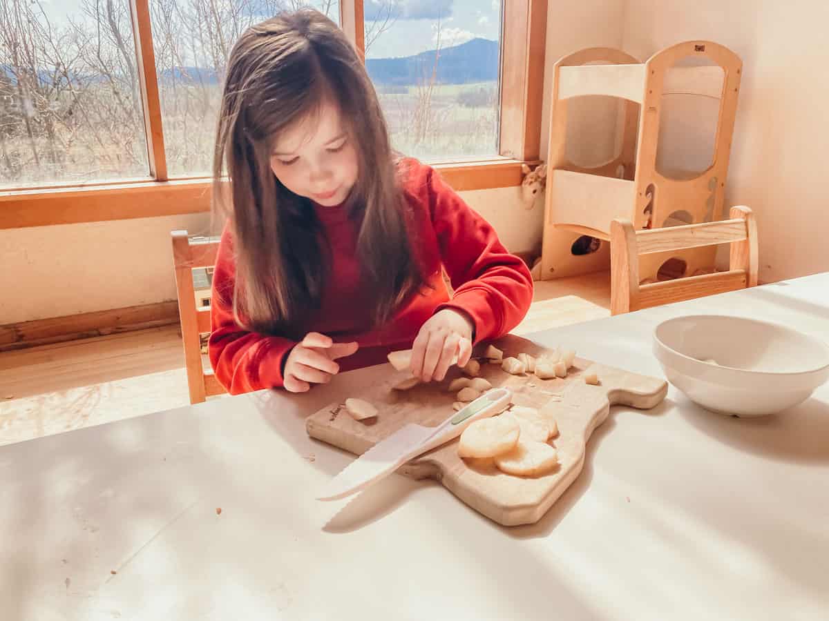 child stacking pieces of a potato on a cutting board