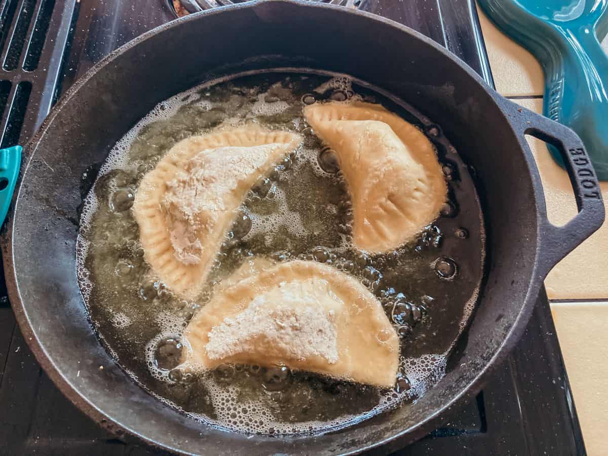 empanadillas frying in a cast iron skillet