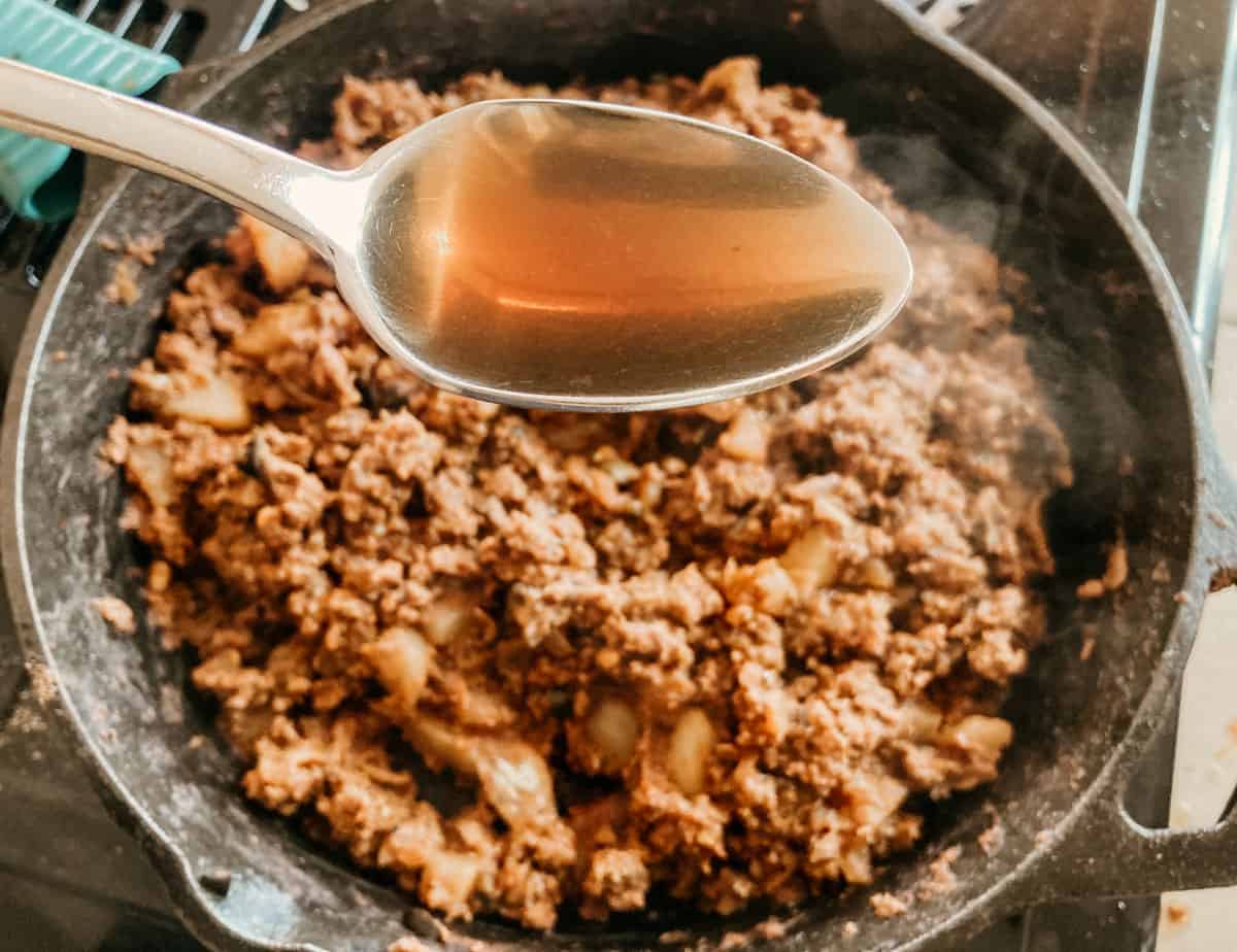 a tablespoon of olive brine over a skillet containing picadillo