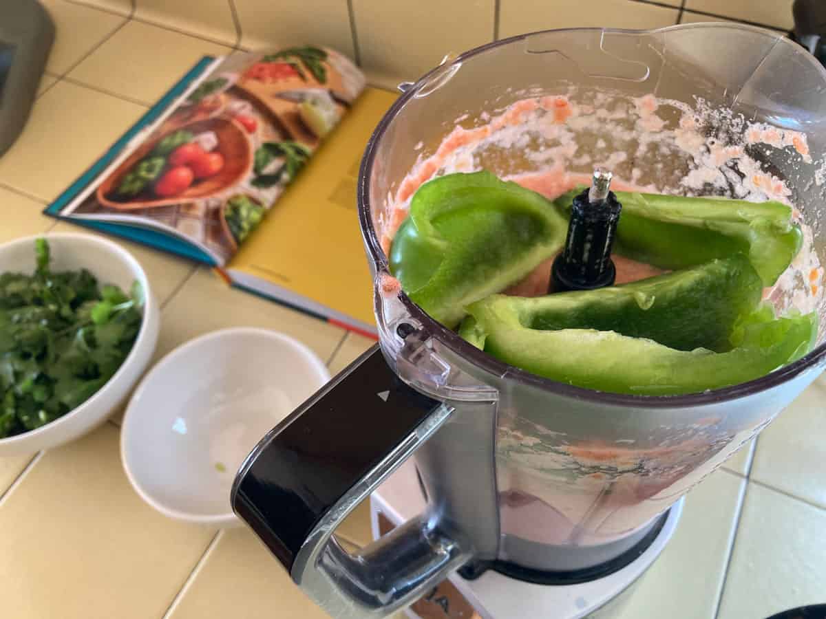 a blender with sofrito ingredients, including bell pepper, inside