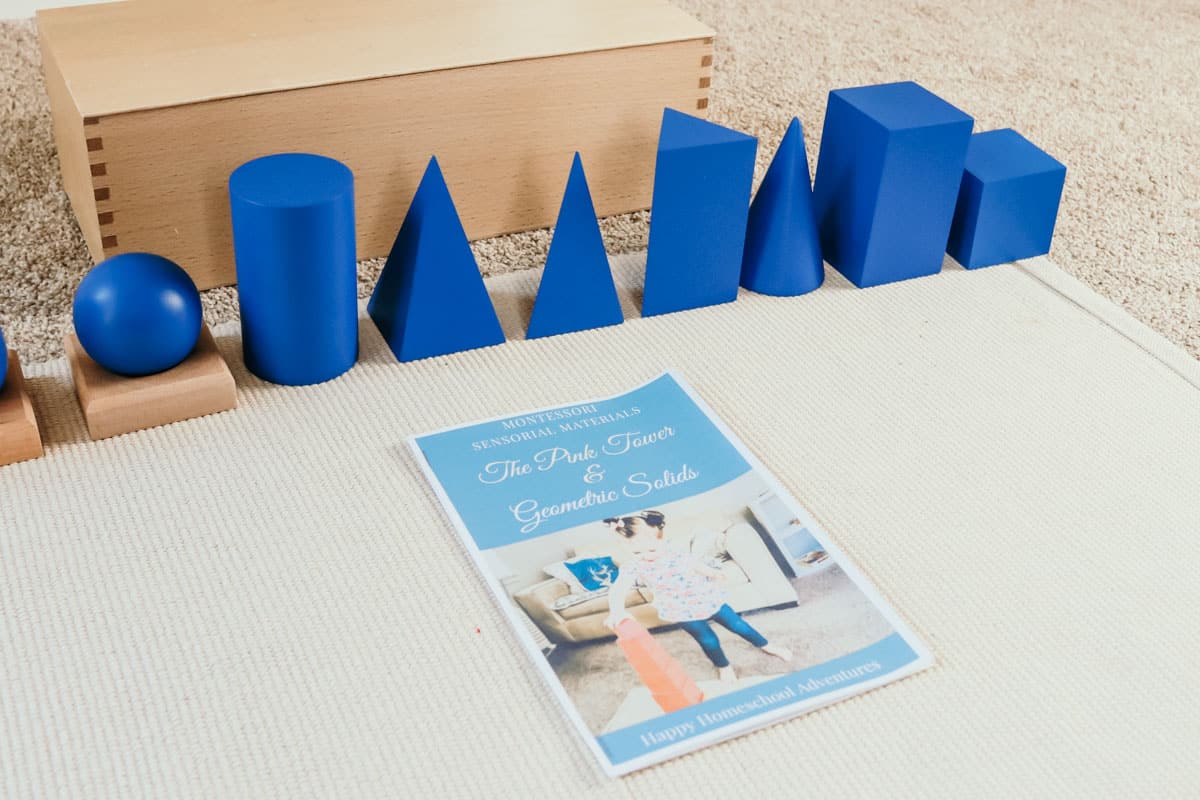 Montessori geometric solids on a mat and a free printable guide on how to use them along with the Pink Tower