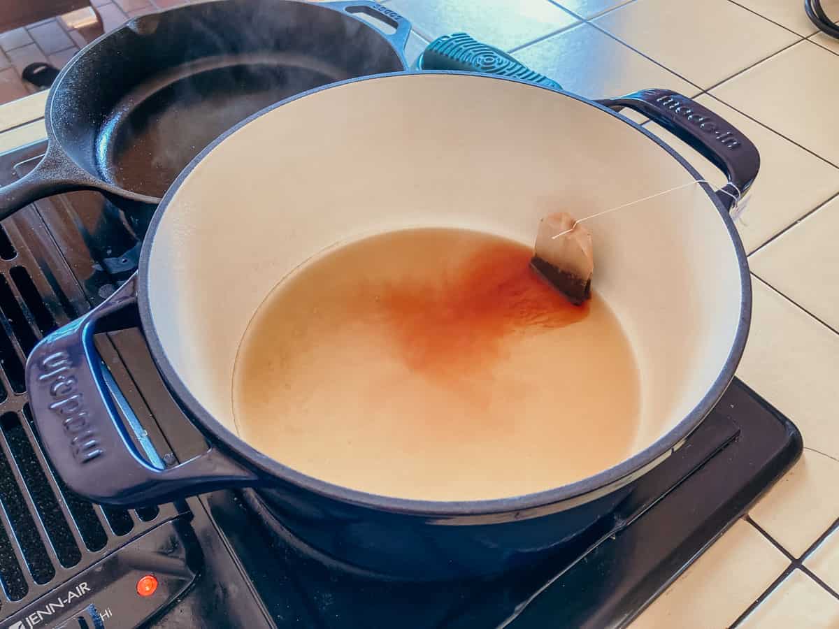 black tea bag, whiskey, and water in a dutch oven