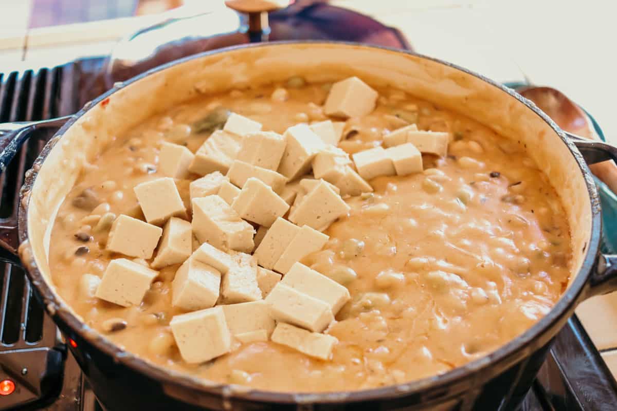 cubes of tofu sitting on top of a Dutch oven with vegetarian gumbo